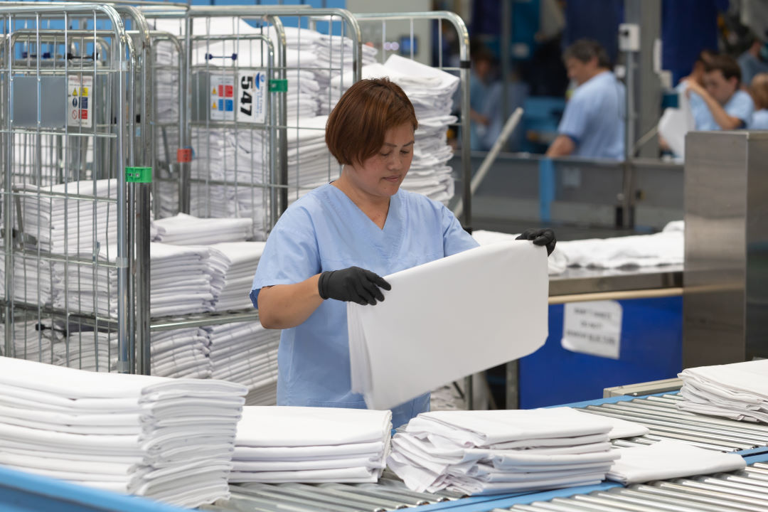 A photo of Holy Cross Services team member working in their commercial laundry.