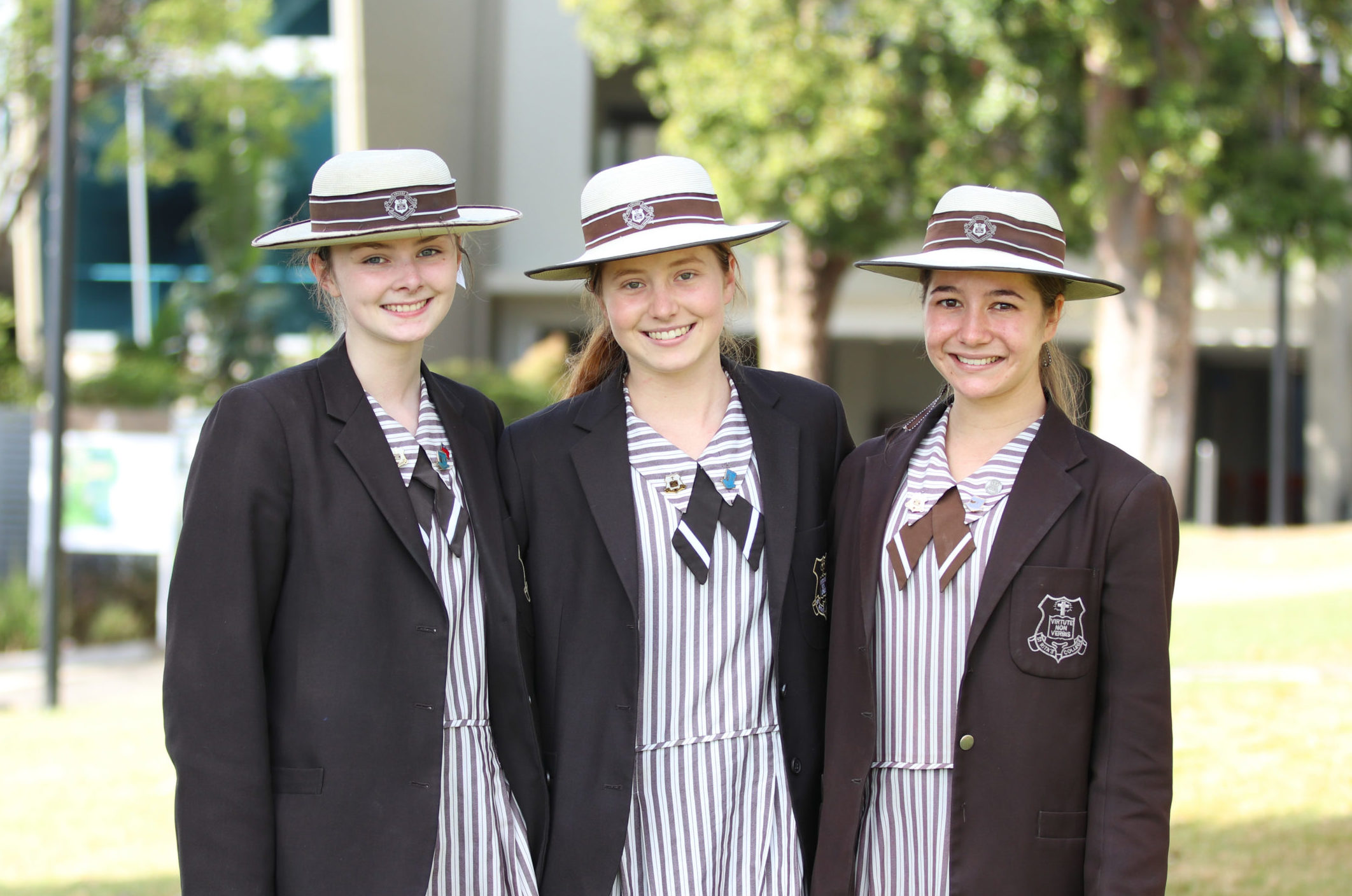 A photo of three St Rita's College students in their school uniforms with hats.