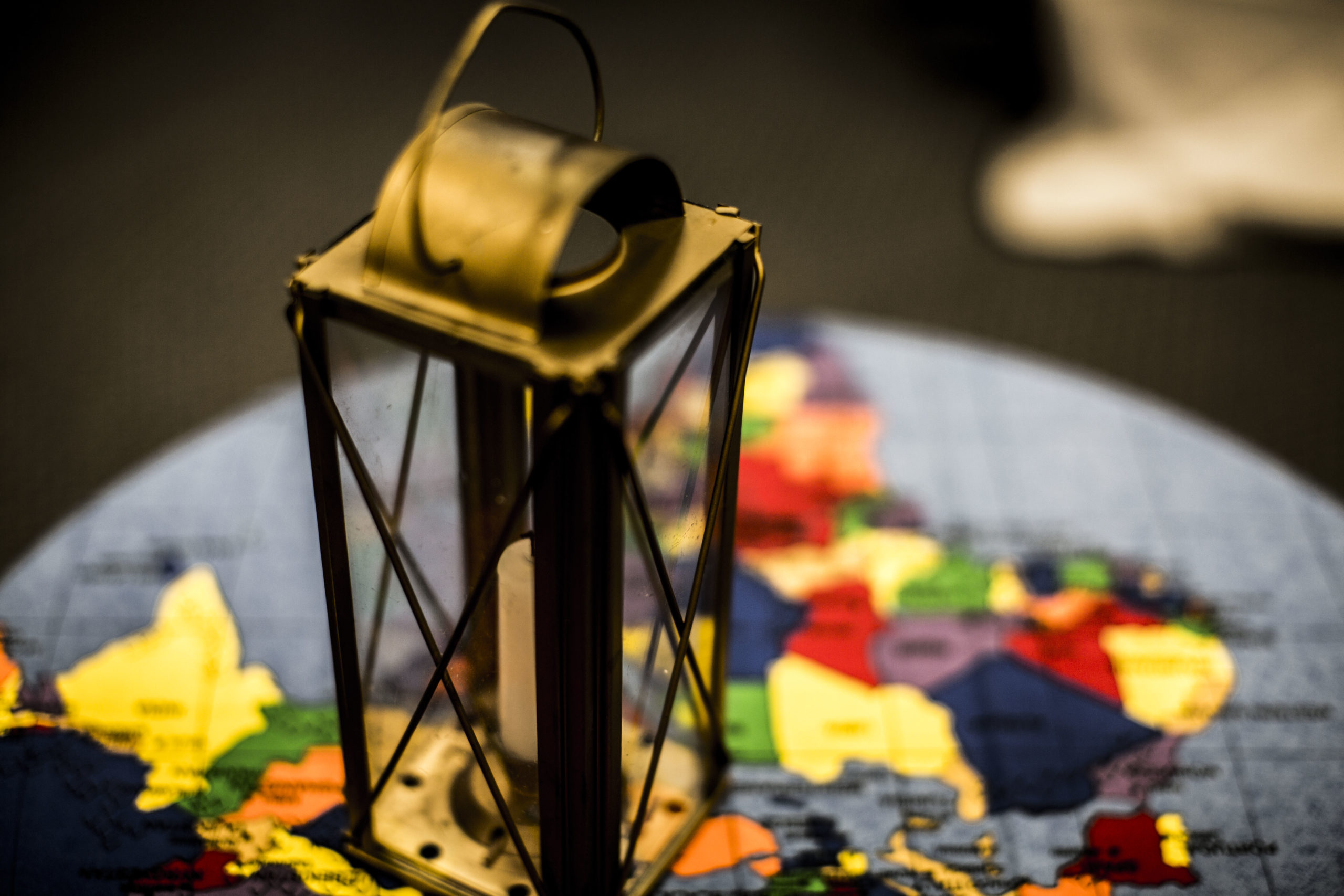 This is a photo of a lantern sitting on top of a map of the world. The map is brightly coloured.