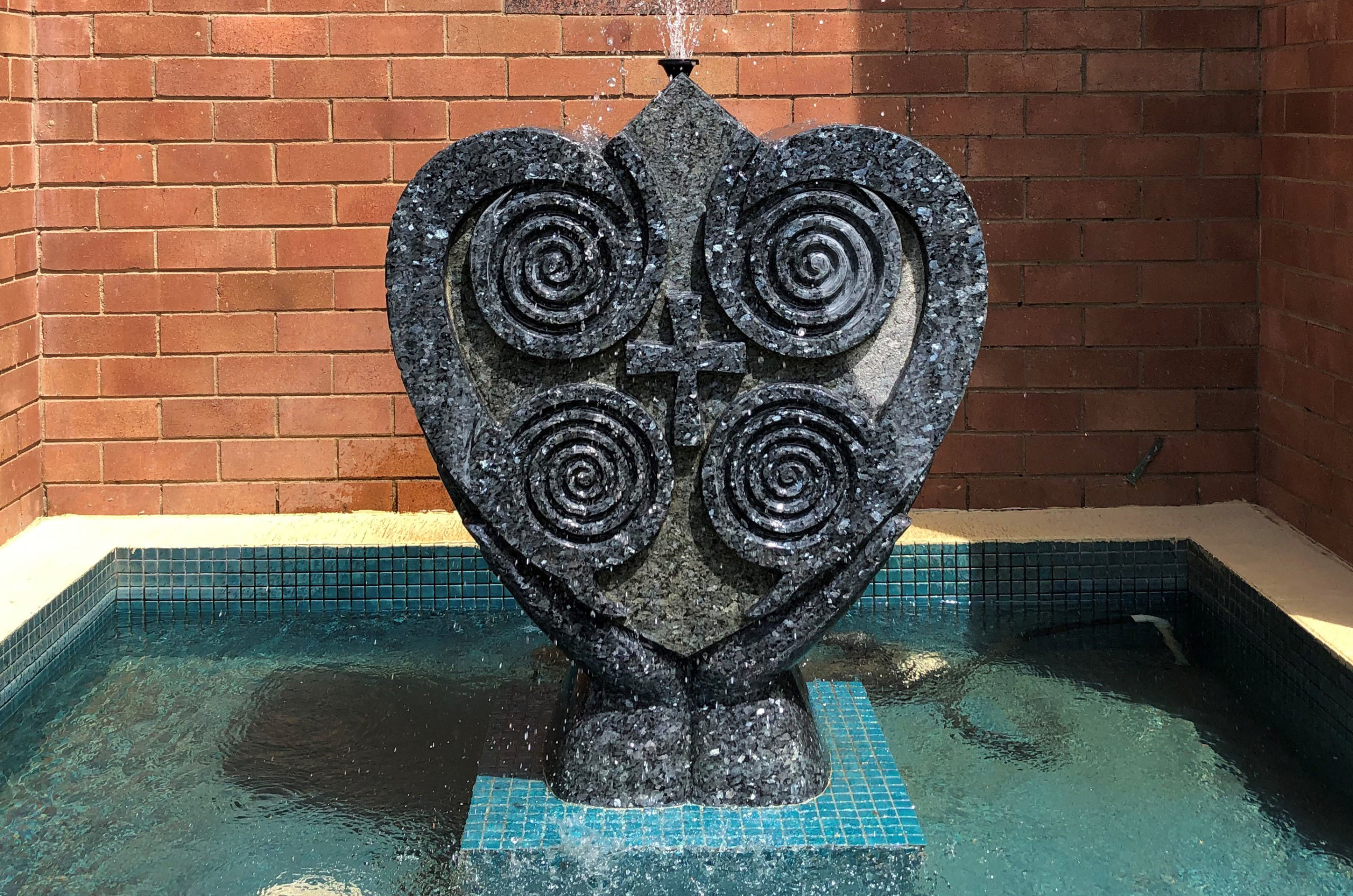 A photo of a statue of the Presentation Heart. The status is made of stone and forms part of a water fountain.