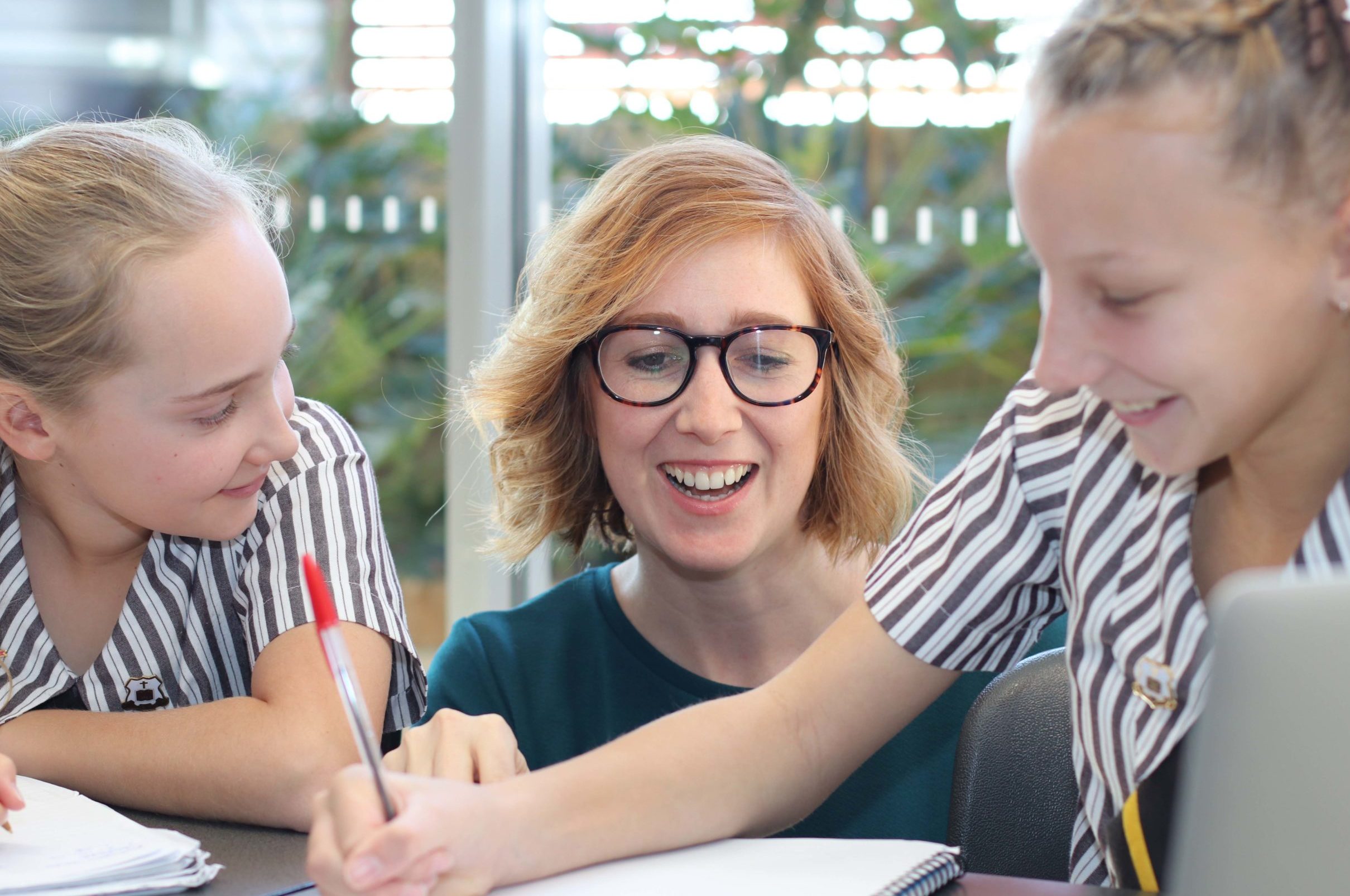 A photo of a teacher assisting two girls doing their school work at St Rita's College.