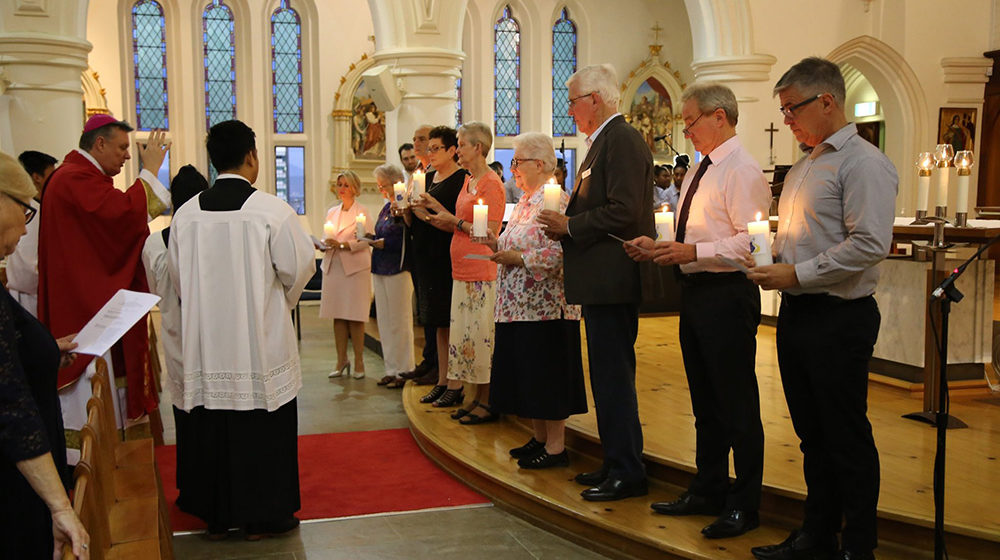 Leaders from Mercy Partners and its ministries holding candles at Sacred Heart Cathedral, Townsville.