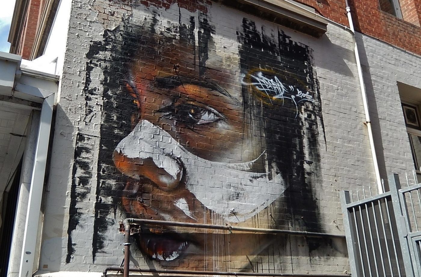 Painted Aboriginal girl’s face on the side of a building in Leigh Street, Adelaide by artist Matt Adnate.