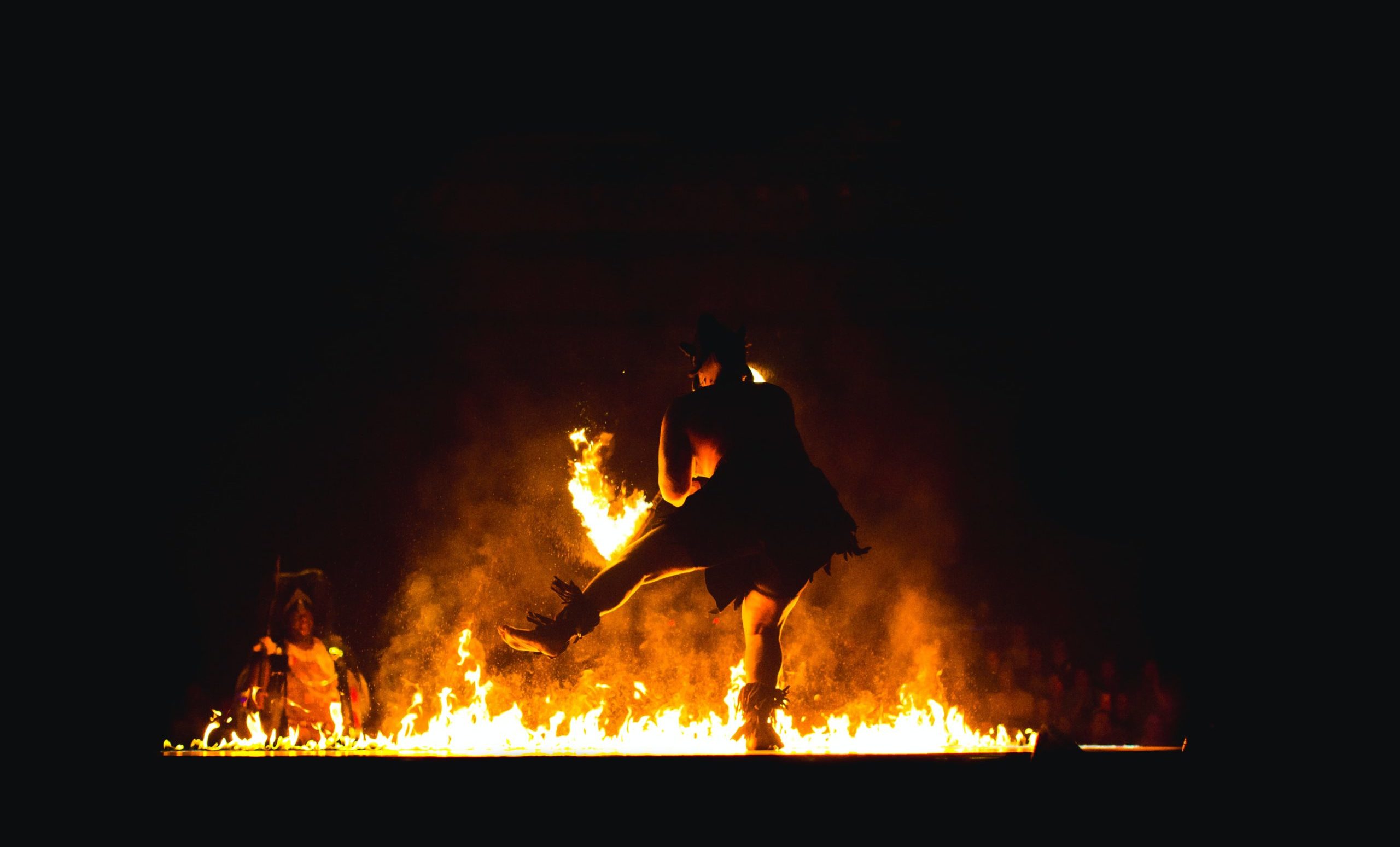 A photograph of a large fire and indigenous dancer..