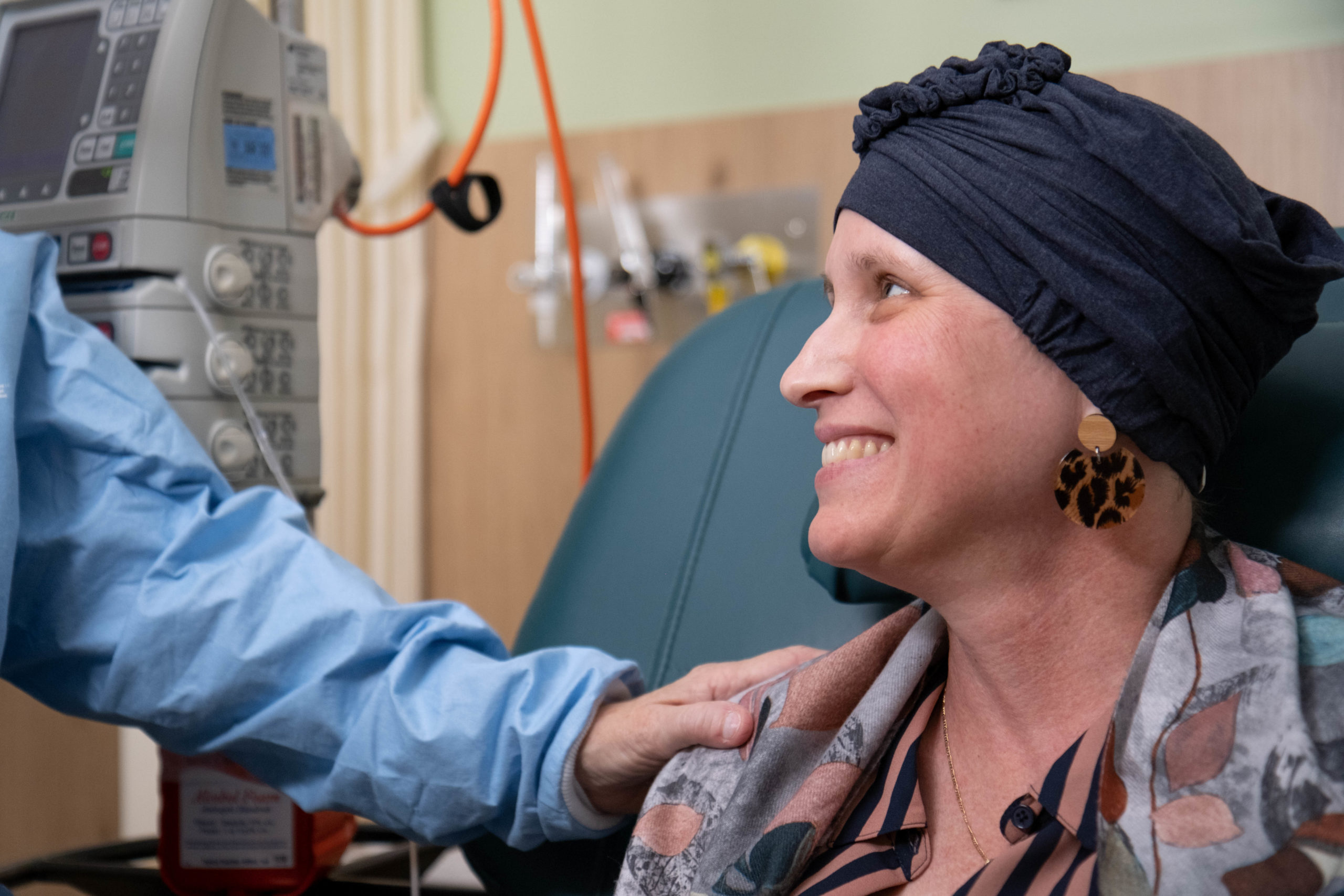 A health worker laying a comforting hand on the shoulder of an oncology patient.