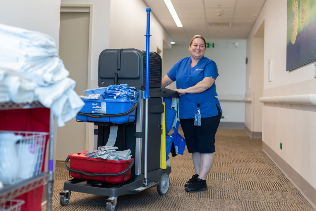 A smiling woman working as a commercial cleaner for Holy Cross Services