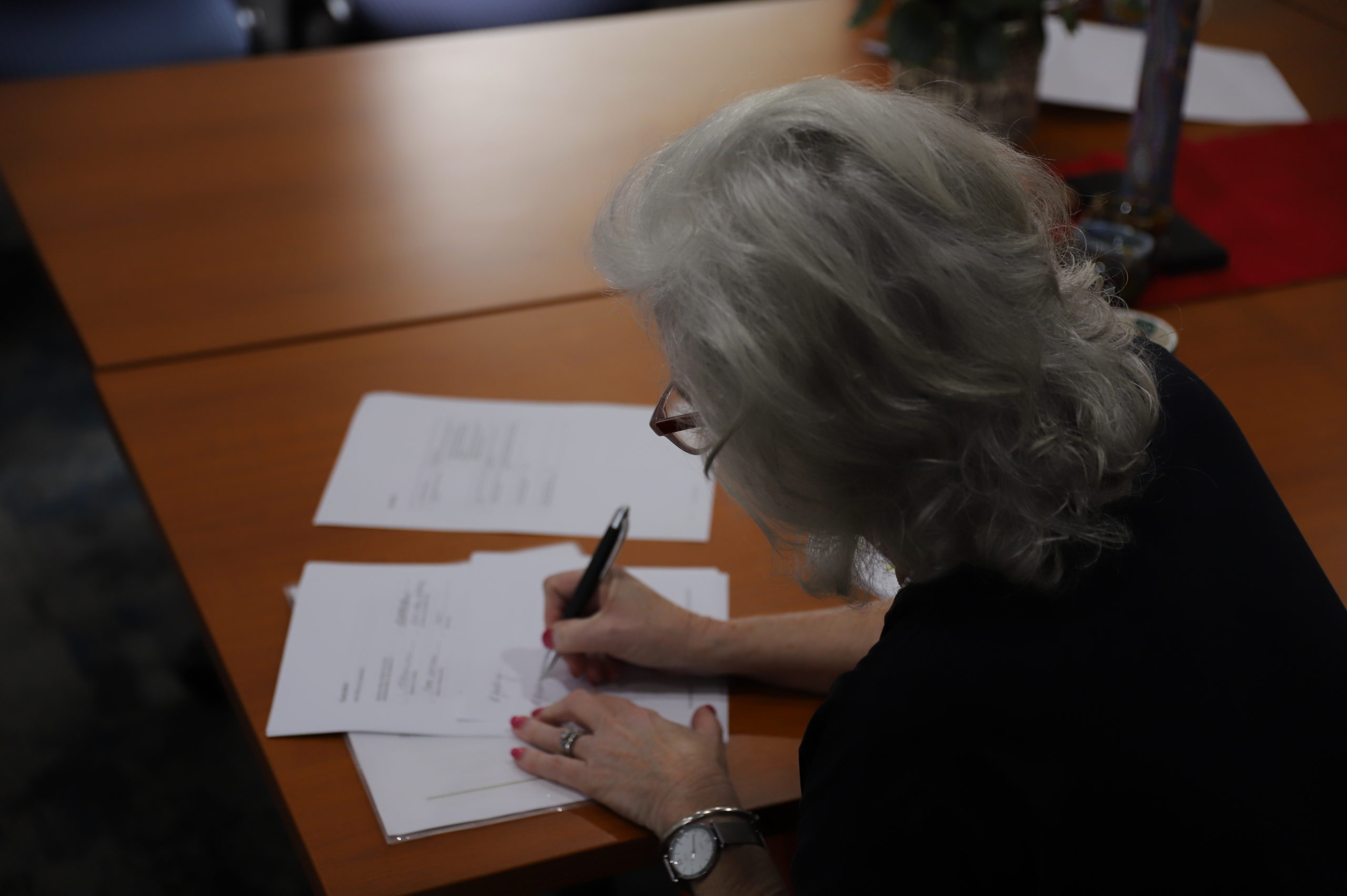 This is a photo of Dr Ricki Jeffery signing governance documentation.