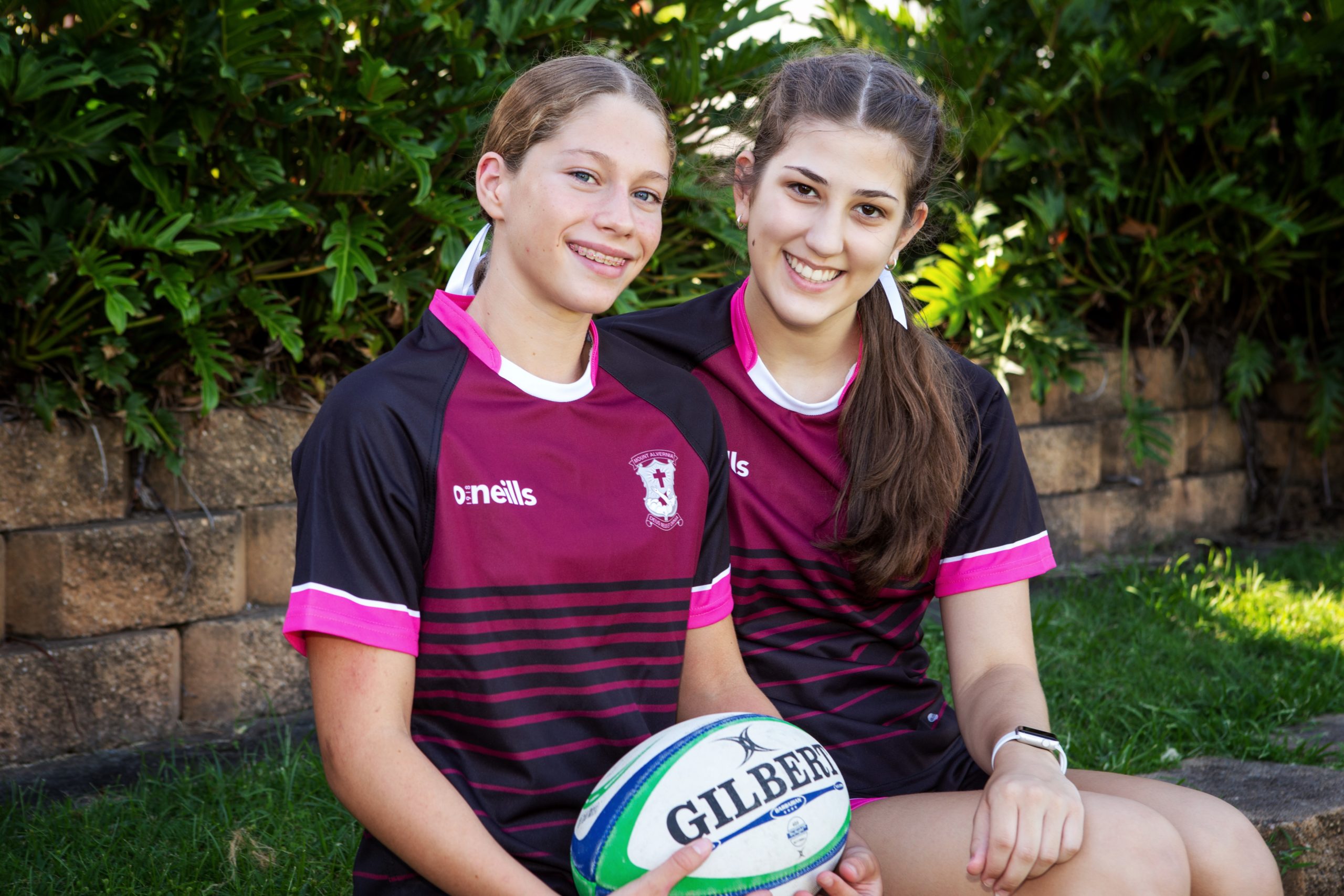 Two students from Mount Alvernia wearing their Rugby Union uniform and holding a rugby ball.