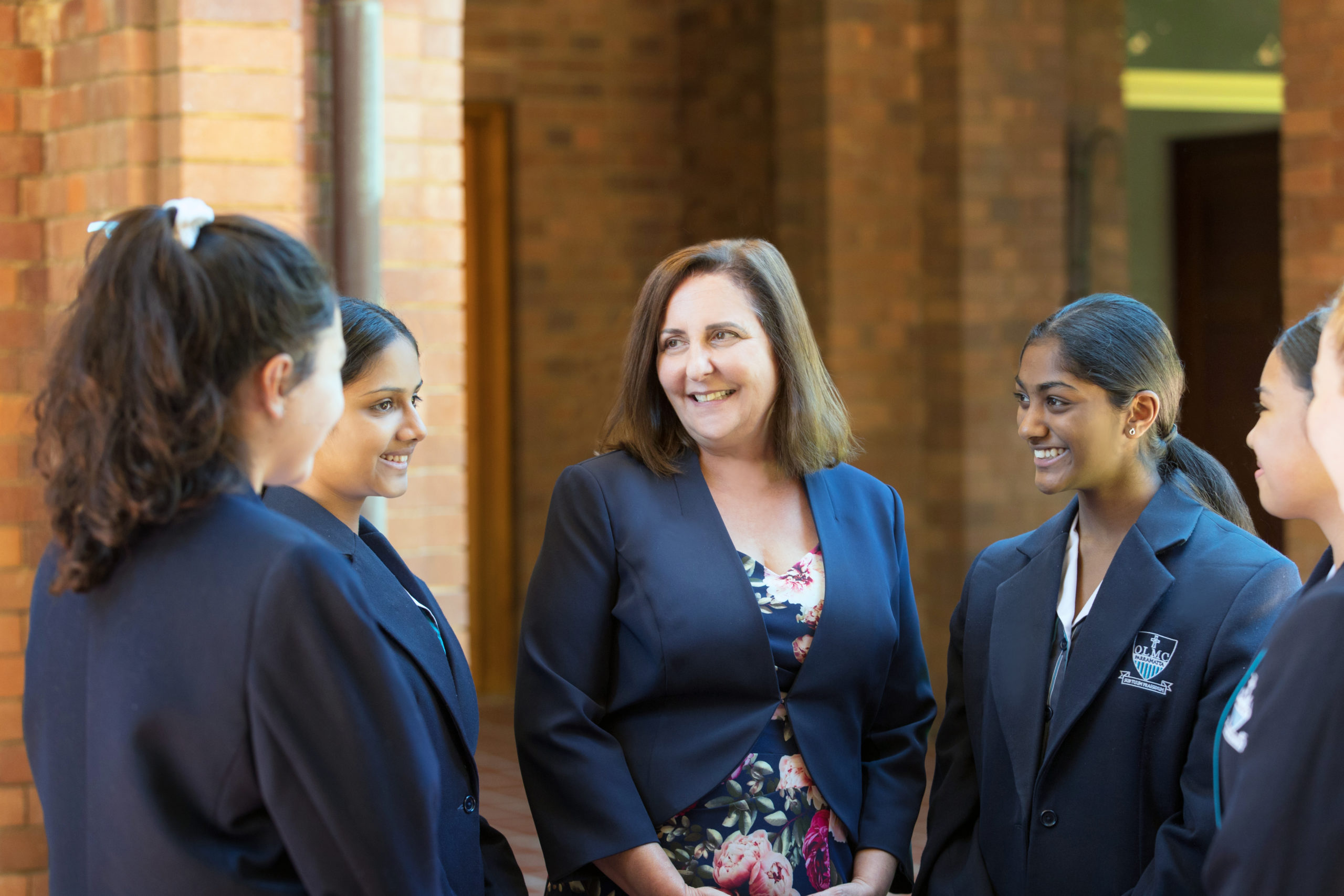 A photo of Our Lady of Mercy College Parramatta's Principal, Ms Lucie Farrugia, who is standing with a group of girls from the school.
