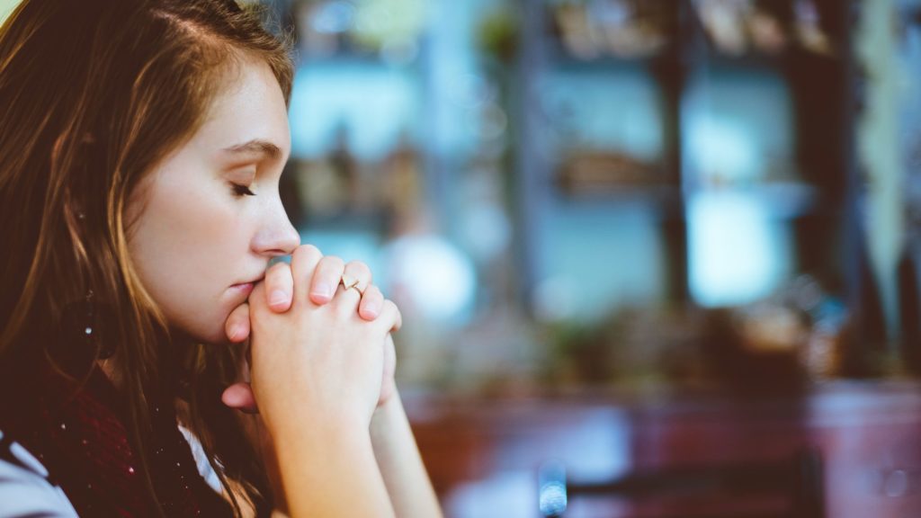 A photograph of a young woman praying.
