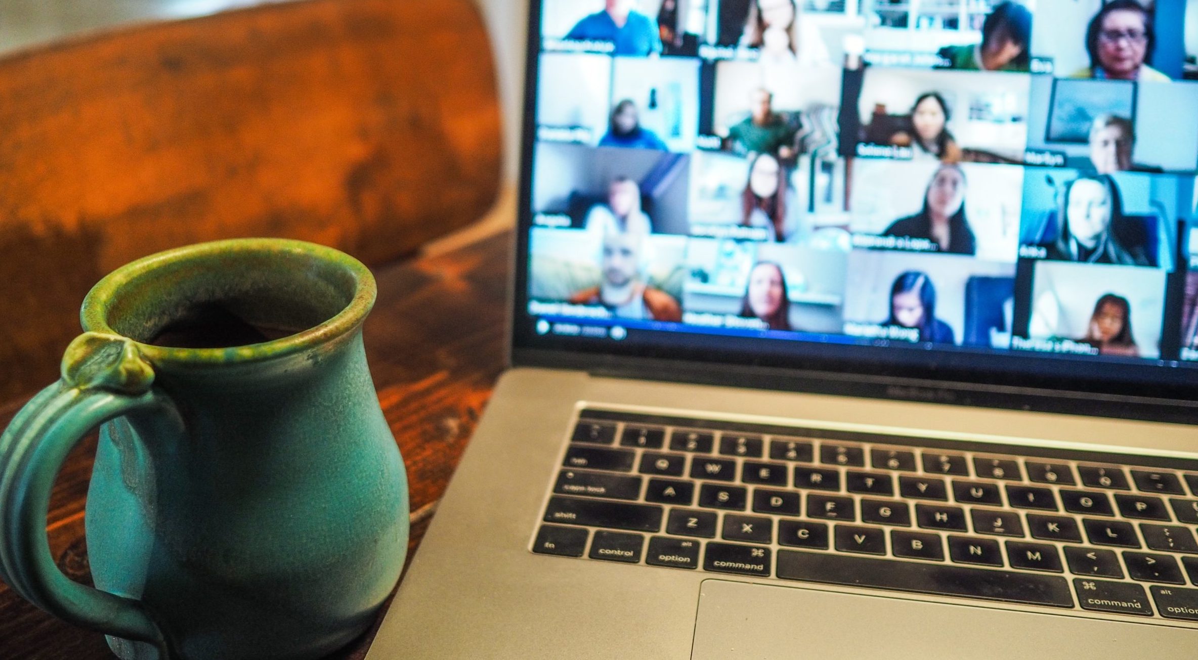A photograph on a mug beside a laptop with images of people in an online meeting.