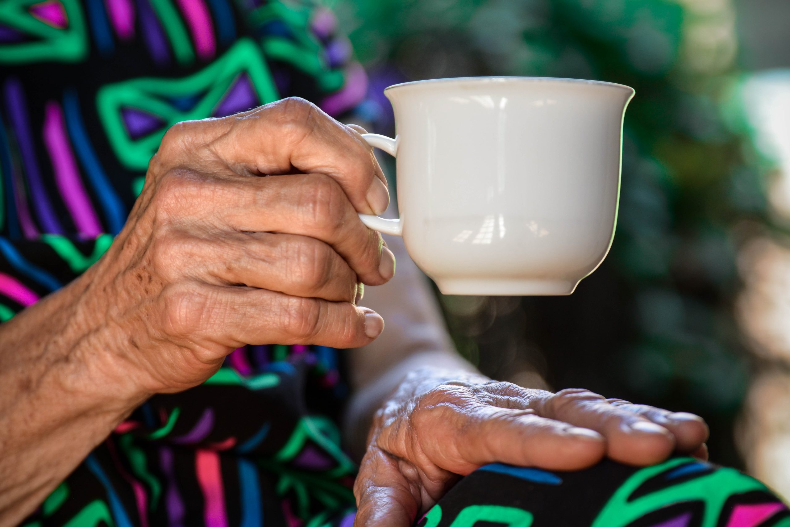 An elderly lady's hand holding a tea cup.