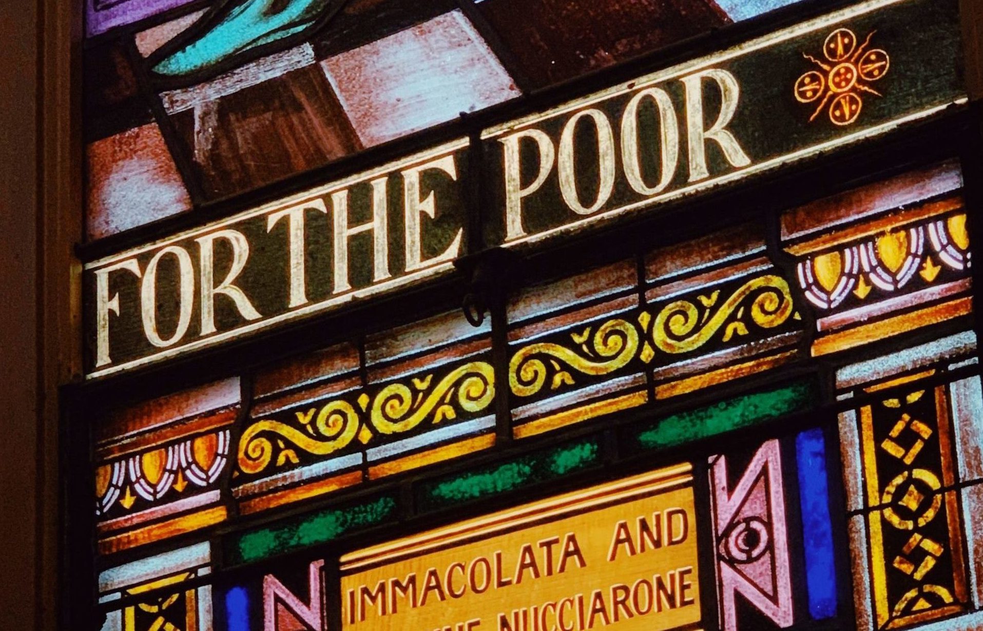 A stained glass window, filled with bright colour and the words