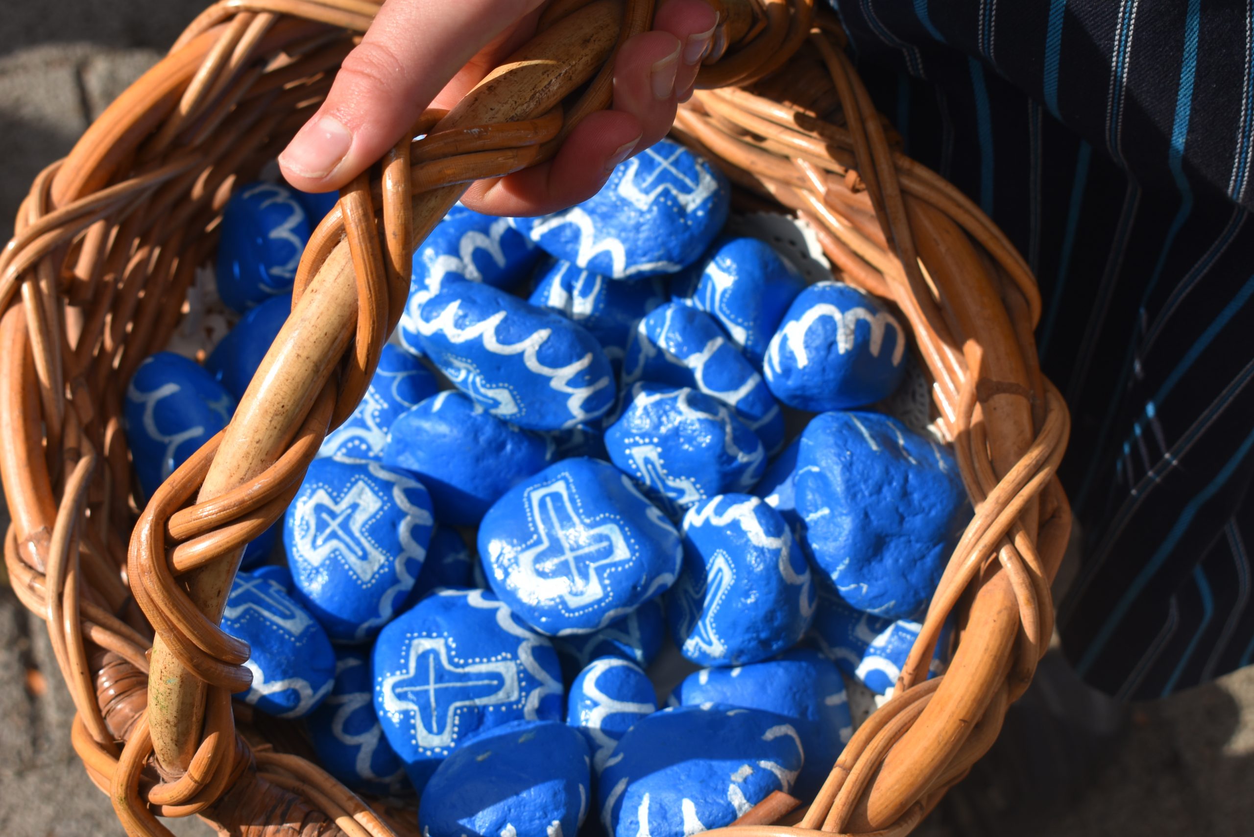 This is a photo of a basket filled with hand painted stones in blue and white.