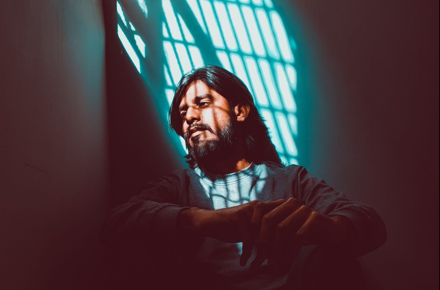 man in prison cell with sunlight shining through the bars on the window onto his face