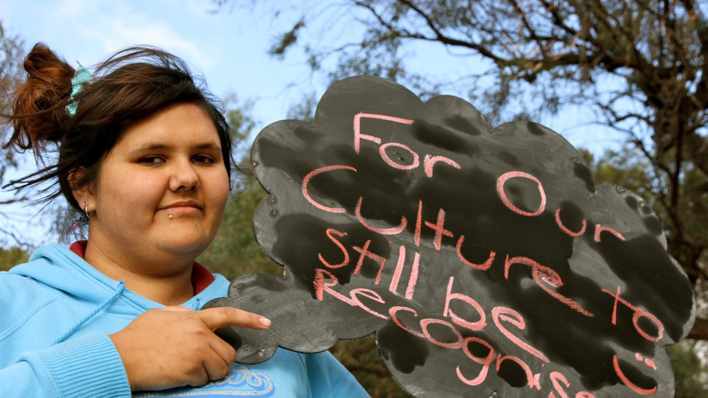 Indigenous girl holding a sign saying 
