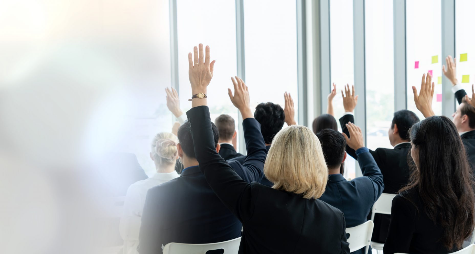Group of business people meeting in a seminar conference widen view . Audience listening to instructor in employee education training session . Office worker community summit forum with speaker .