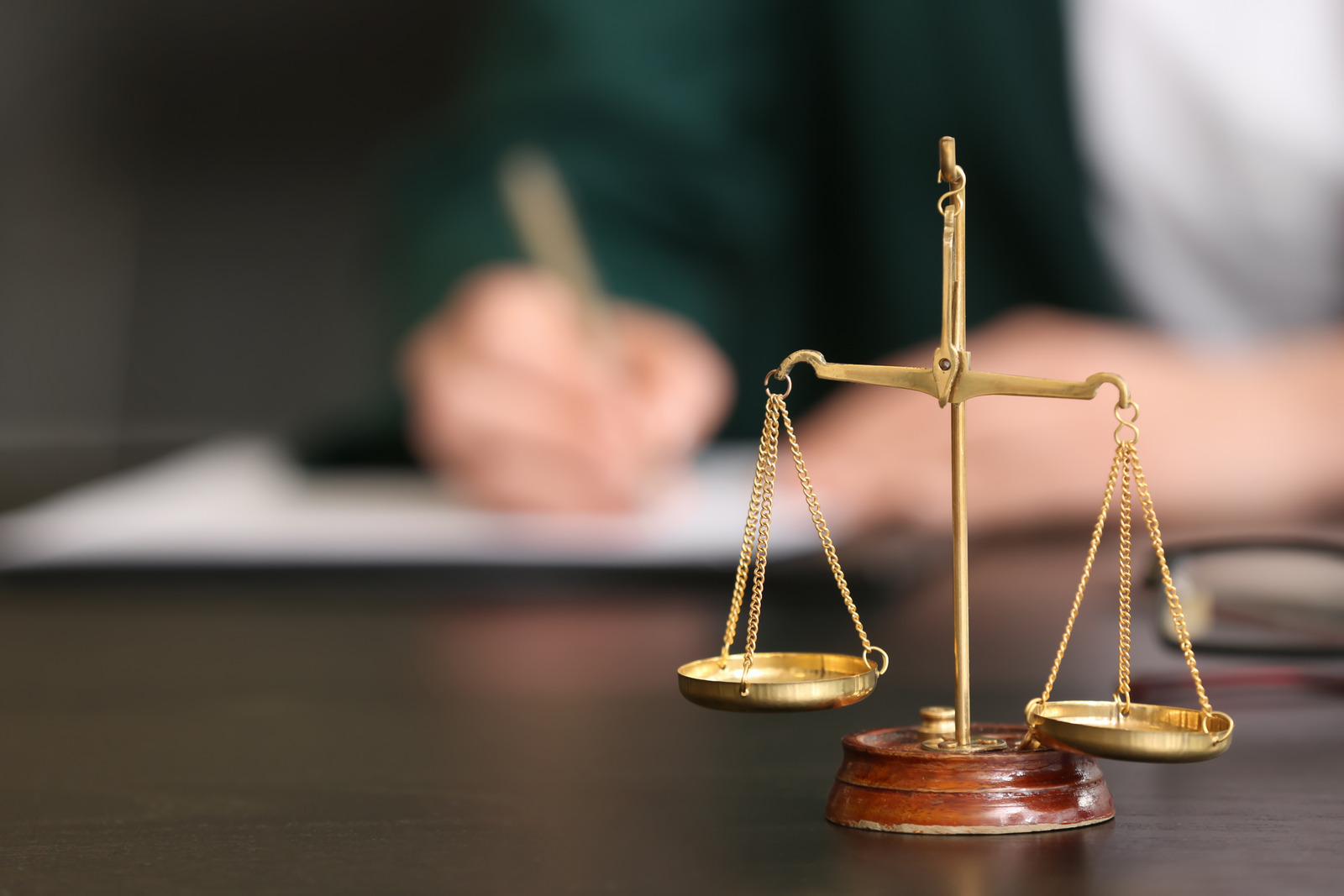 Scales of justice on table of female judge in courtroom, closeup